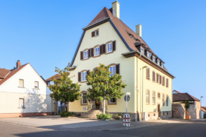 Ein gelbes Haus, vor dem zwei Bäume stehen.