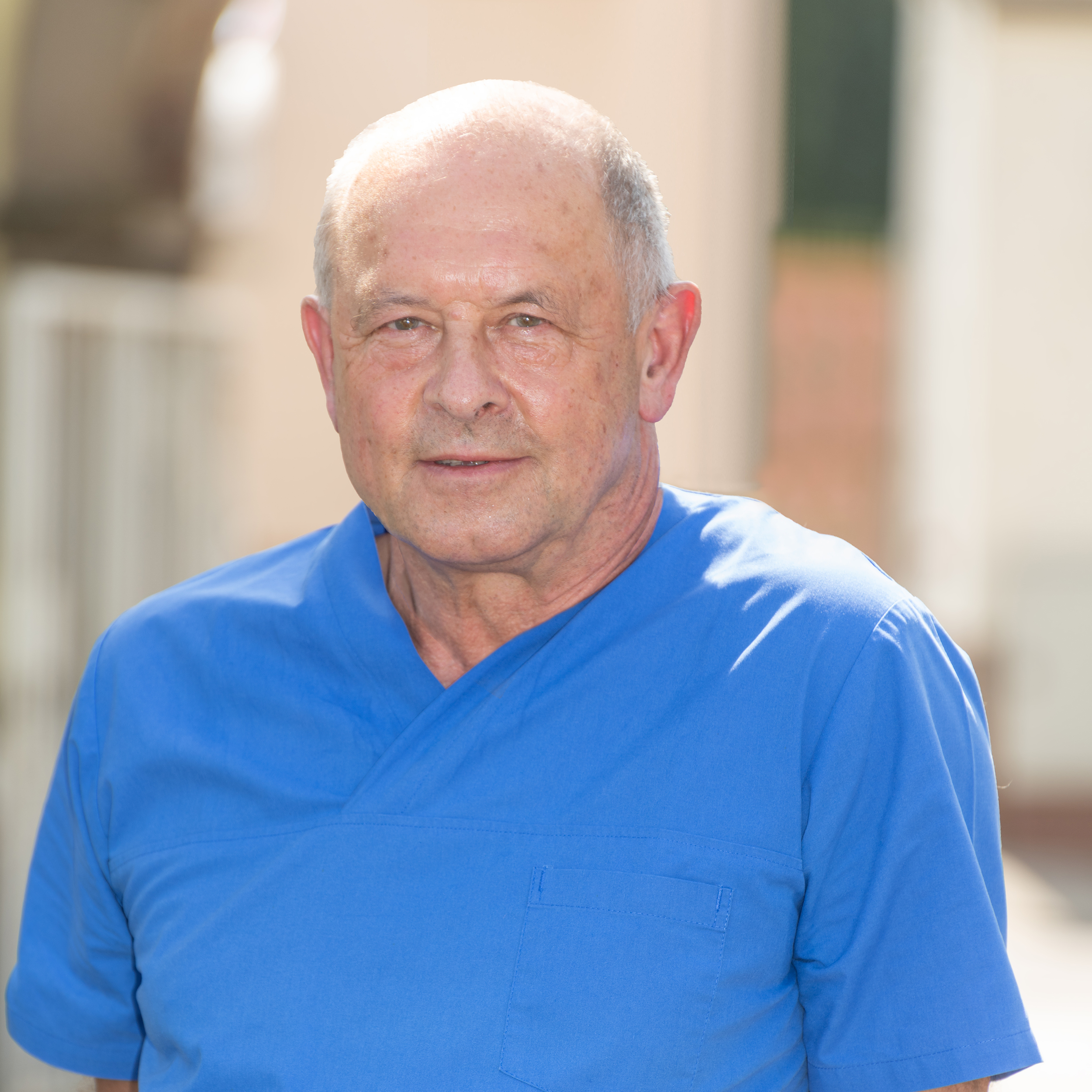 Porträtfoto von Tierarzt Dr. med. vet. Holger Zieris der Tierarztpraxis Hettenleidelheim, lächelnd in blauem Praxis-Kasack vor hellem Hintergrund